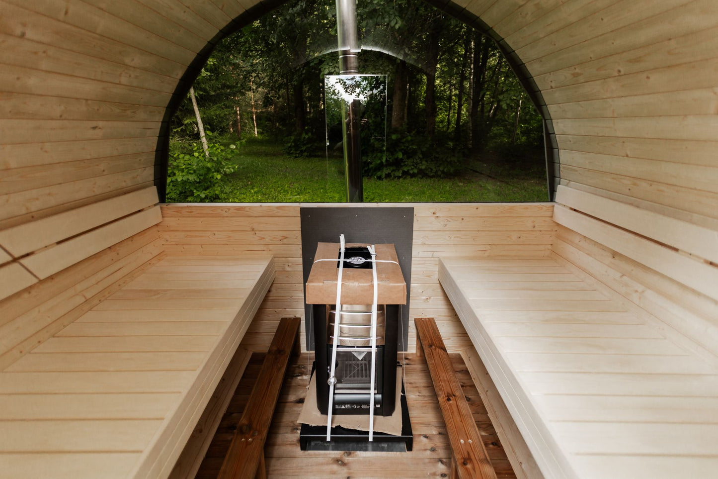 Runde Außensauna aus hochwertigem Fichten- oder Thermoholz, geeignet für 4–Personen. Mit Lindenholz-Bänken, Bitumenschindeln-Dach, Sicherheitsglas-Türen und Harvia-Beleuchtung.Bild innen